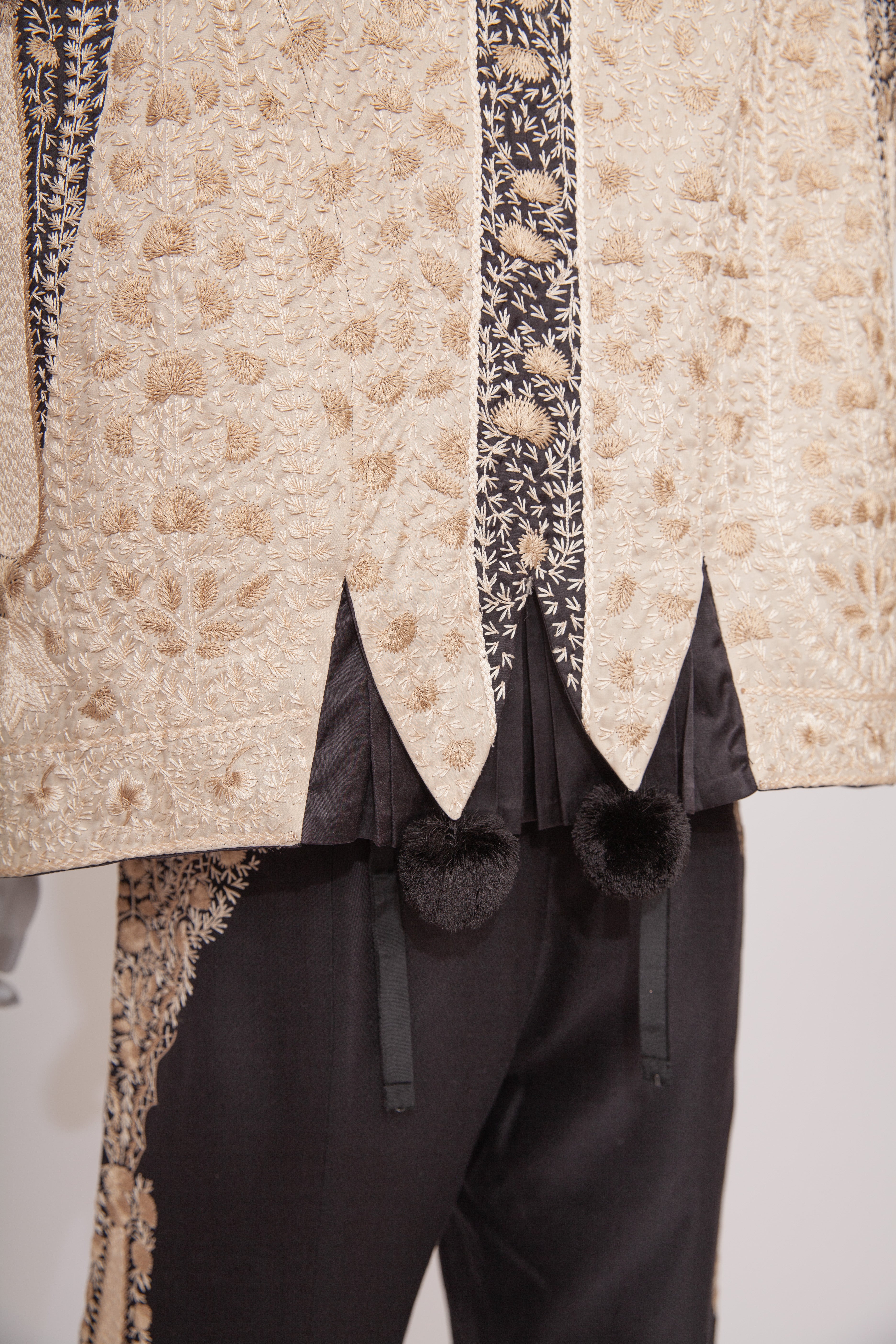 Close-up of a textured beige coat with black trim on a white background